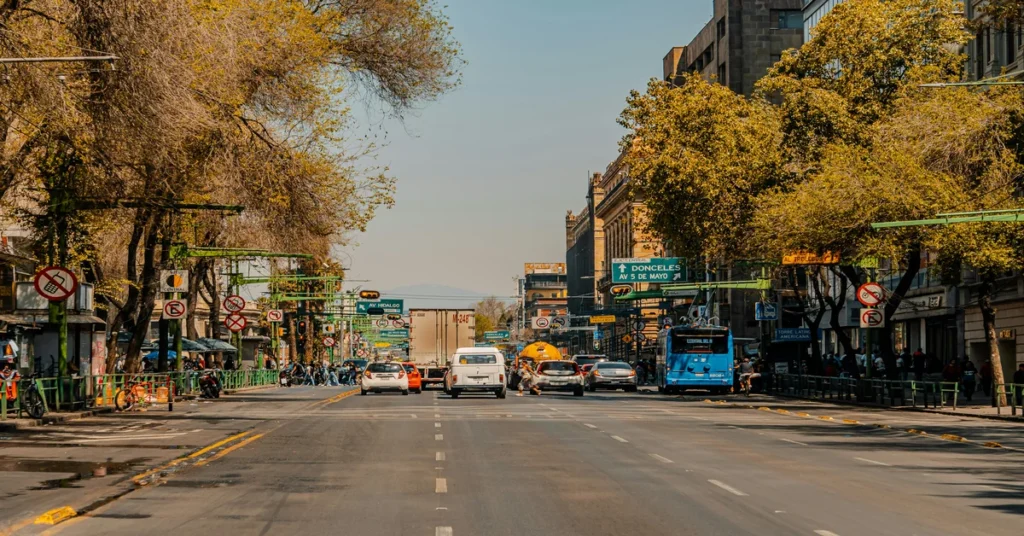 Wide street view of Avenida Hidalgo in Mexico City with cars, buses, and surrounding trees under a clear sky